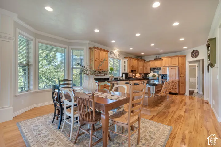 Kitchen featuring wood cabinetry, integrated island, recessed lighting, and wood-finish flooring with an expansive bay window