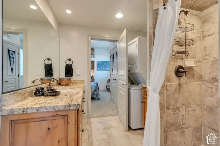 Bathroom featuring a natural stone-topped vanity with undermount sink, recessed lighting, tile flooring, and a walk-in shower with tile surround