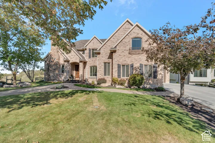 Multi-gabled exterior featuring brick masonry, arched entryway, dark decorative shutters, and stone foundation accents
