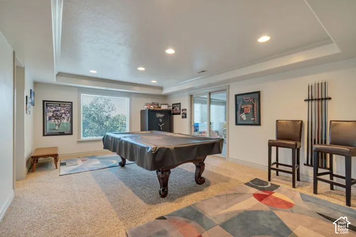 Interior space featuring a recessed tray ceiling, recessed lighting, carpeted flooring, and glass sliding doors