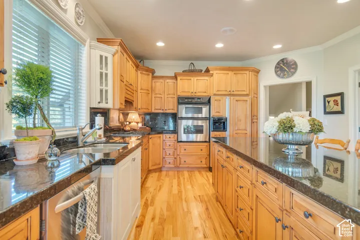 Kitchen featuring wood cabinetry, expansive stone countertops, stainless steel double wall ovens, a center island, and wood-finish flooring