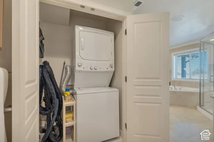 Laundry closet located in master En-suite bathroom.  featuring a stackable washer and dryer unit enclosed by paneled doors