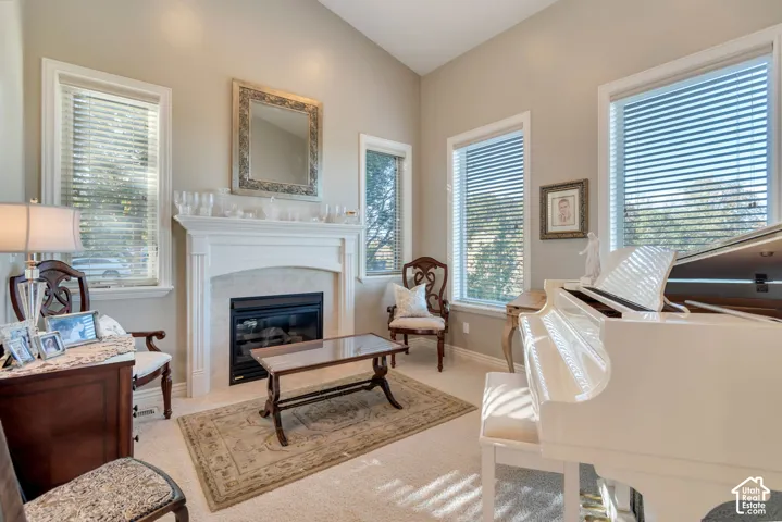 Vaulted ceilings, fireplace with a decorative mantel, multiple windows, and neutral carpeting