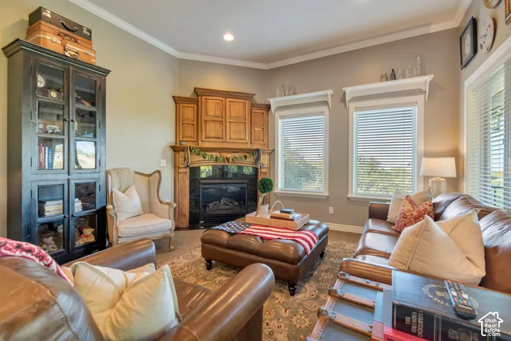 Fireplace featuring a dark stone surround and wood mantel, built-in wooden cabinetry, floor-to-ceiling recessed shelving, crown molding, and dual windows with window blinds