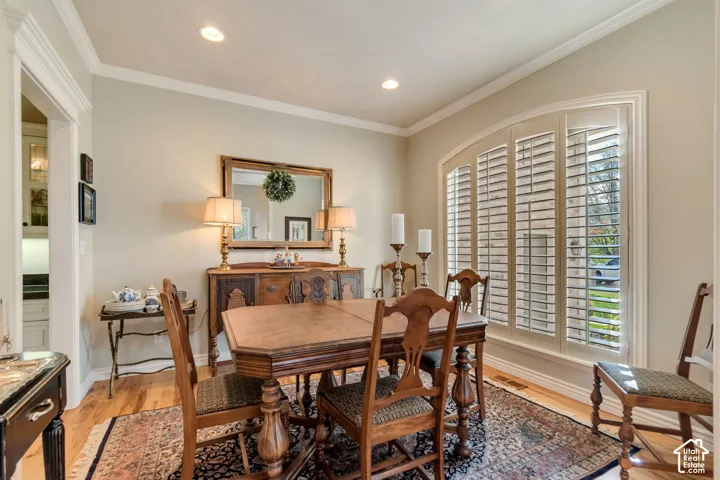 Room featuring crown molding, recessed lighting, wood-finish flooring, and an arched window equipped with plantation shutters