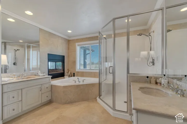 Master Bath En-Suite Bath. Dual vanity featuring stone countertops and integrated sinks, corner soaking tub, fireplace with black surround, and a glass-enclosed shower with a built-in seat
