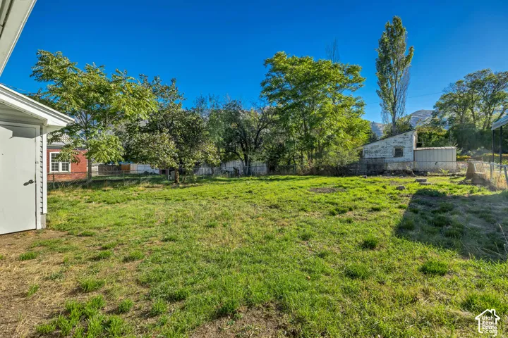 Expansive backyard featuring mature trees, mountain backdrop, and partial fencing