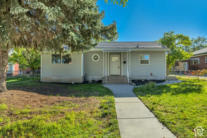 Single-story residence featuring horizontal siding, a gabled roof, decorative circular accent window, iron porch supports, and a concrete walkway