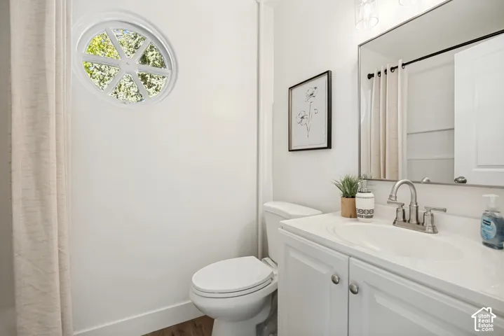 Bathroom featuring a circular accent window, white vanity cabinet with an integrated sink, brushed-nickel faucet, and a large-format rectangular mirror