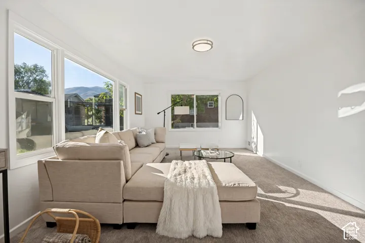 Living area featuring expansive windows, neutral carpeting, recessed ceiling lighting, and mountain scenery