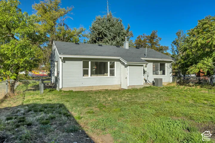 Exterior rear elevation featuring vinyl siding, asphalt shingle roofing, large picture windows, and an enclosed backyard with chain-link fencing