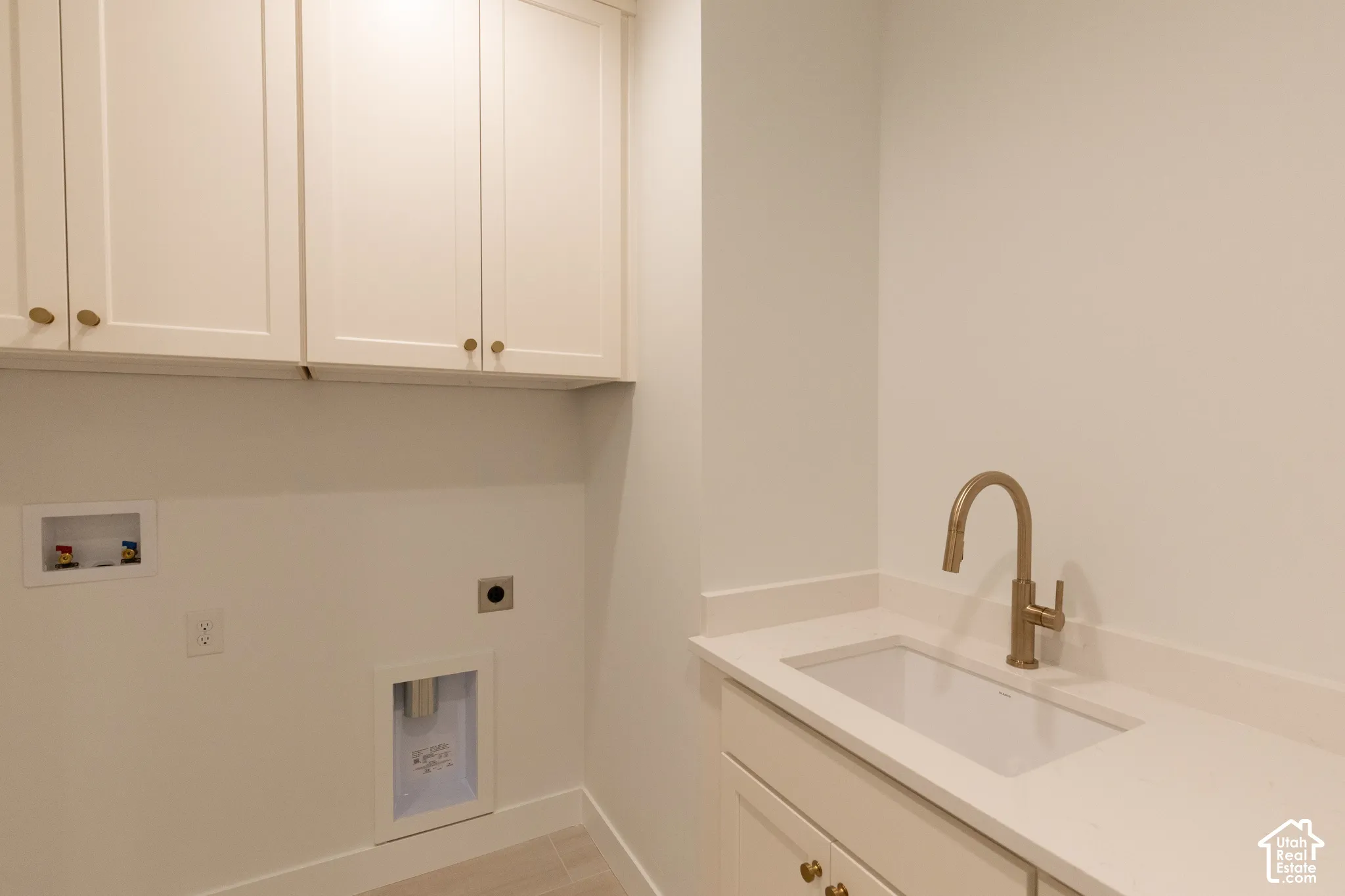 Shaker-style cabinetry, white quartz countertop, undermount sink, and metallic finish faucet