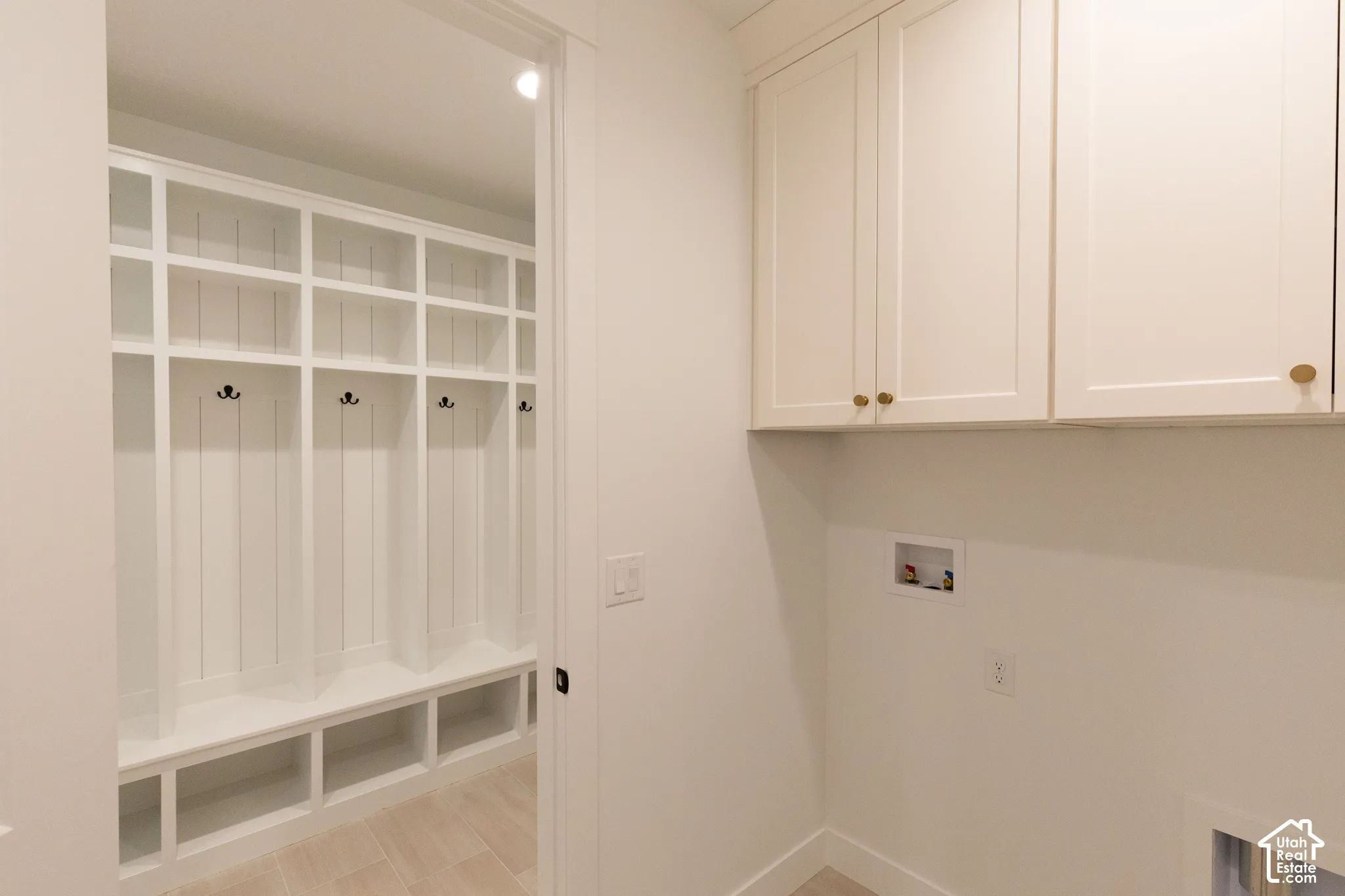 Custom built-in locker storage with integrated bench seating, neutral shaker-style cabinetry, and tile flooring