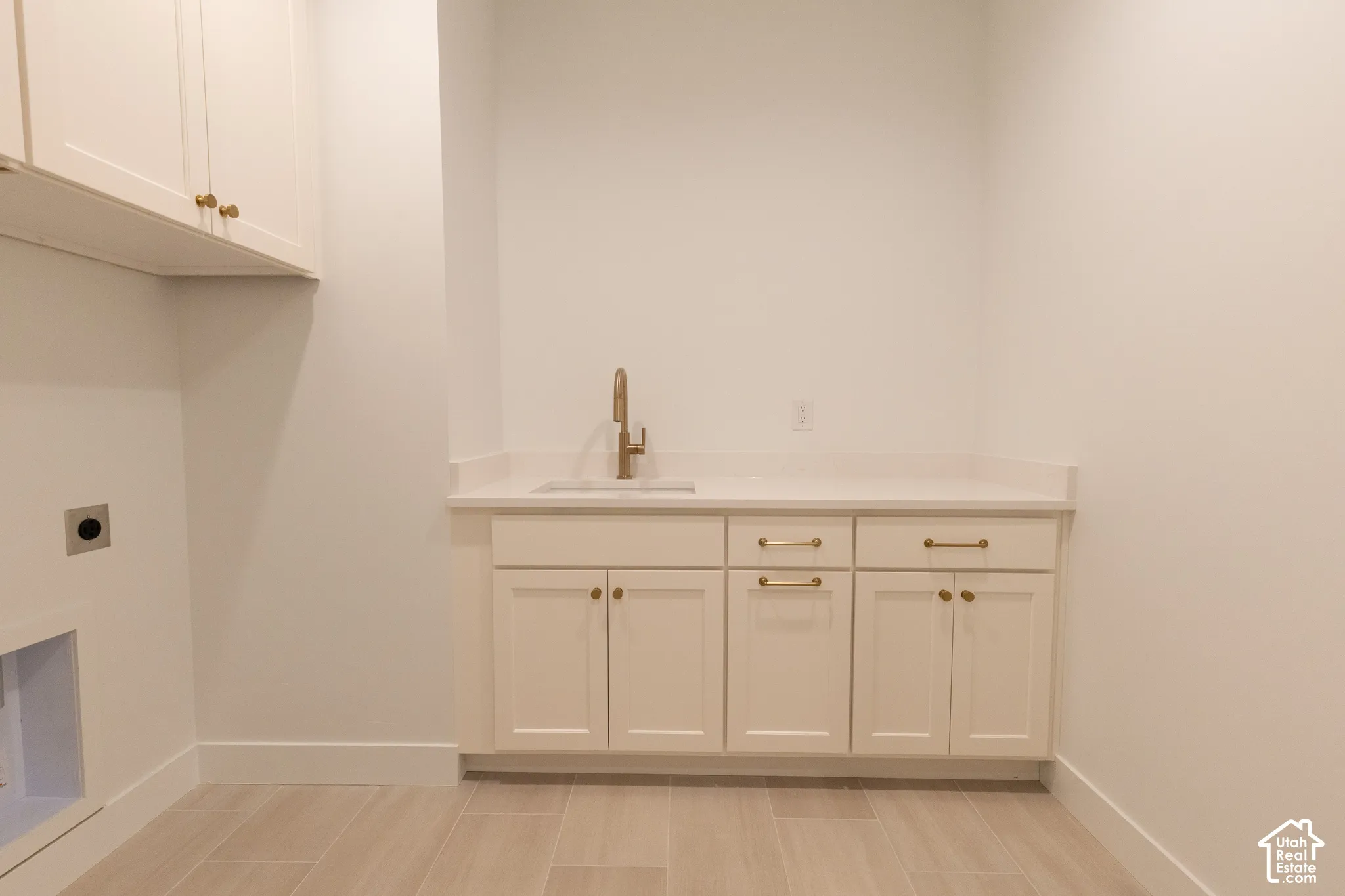 Built-in cabinetry featuring shaker-style doors, stone-surface countertop, undermount sink with a metallic-finish faucet, and tile flooring