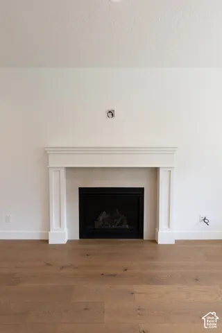 Fireplace featuring a white mantel, stone-tile surround, black metal firebox, and wood-finish flooring