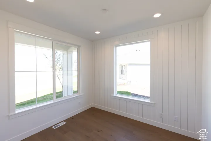 Room featuring vertical board-and-batten wall paneling, wood-finish flooring, recessed lighting, and large windows with integrated grids