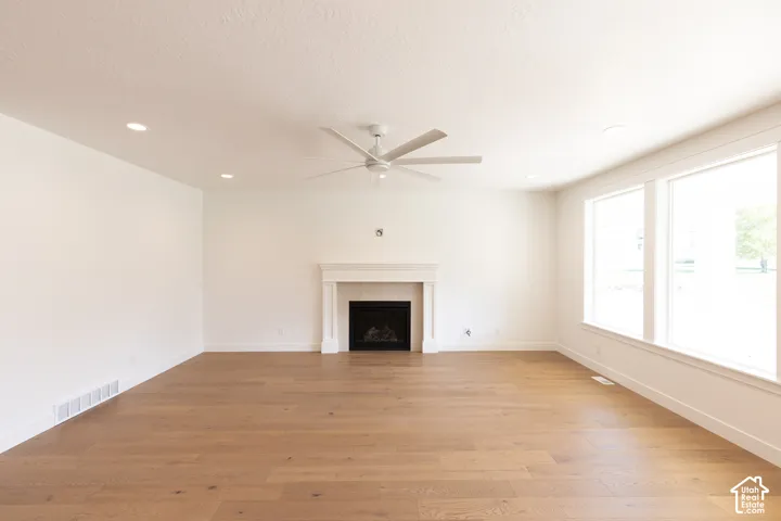 Interior space featuring wood-finish flooring, a fireplace with a decorative mantel, recessed lighting, and a ceiling fan