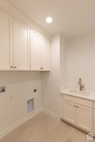Laundry room featuring white Shaker-style cabinetry, a drop-in sink with a high-arch faucet, a stone-composite countertop, and wood-finish tile flooring