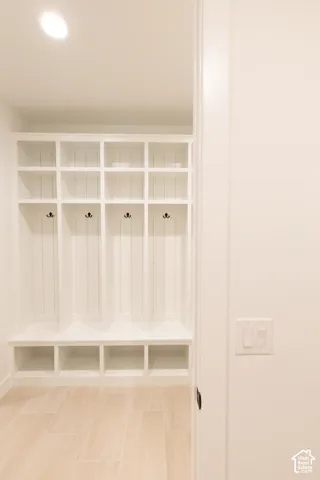 Built-in white cabinetry featuring vertical shiplap detailing, open cubby storage, and matte black hardware, finished with wood-finish flooring and recessed ceiling lighting