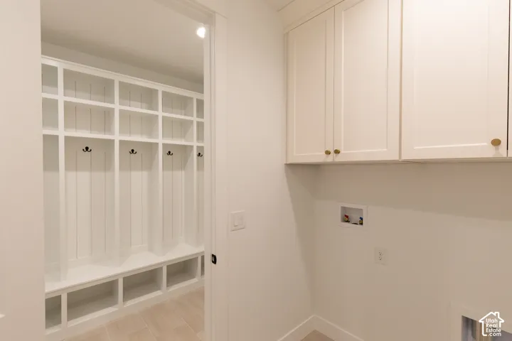 Custom built-in locker storage with integrated bench seating, neutral shaker-style cabinetry, and tile flooring