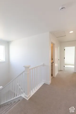White staircase railing with square newel posts, wall-to-wall carpeting, and recessed lighting