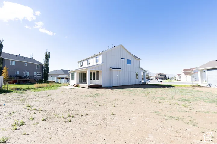 Two-story residence featuring white board-and-batten siding, a covered rear patio, and expansive yard space