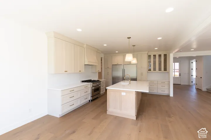 Kitchen featuring light-finish cabinetry, a center island with quartz countertops, wood-finish flooring, recessed lighting, and stainless steel range