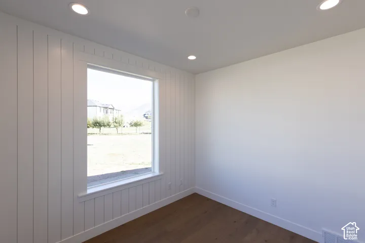 Vertical shiplap accent wall, wood-finish flooring, and recessed ceiling lighting