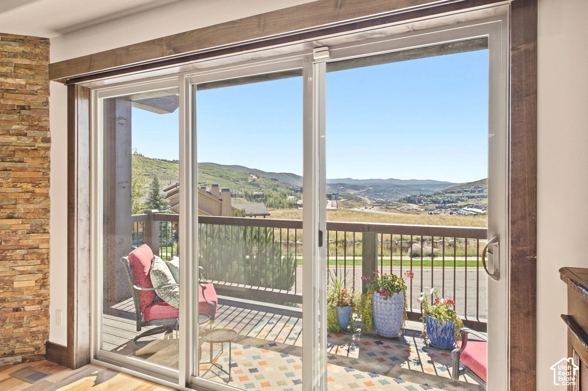 Large sliding glass doors with custom wood trim and an exterior balcony featuring metal railings and mountain scenery