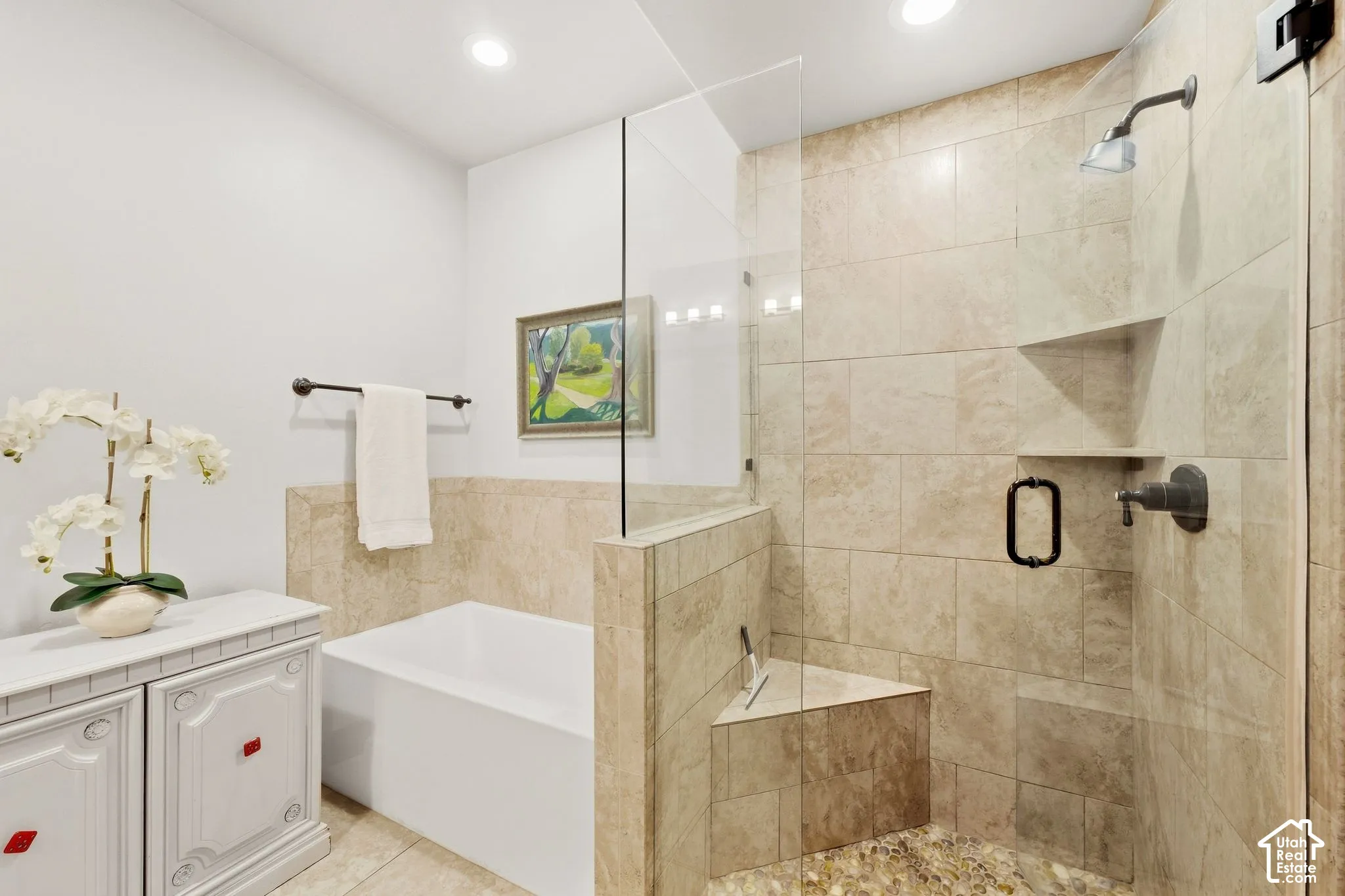 Bathroom featuring a deep soaking tub and a walk-in shower with stone-tile surround, integrated corner bench, frameless glass enclosure, and matte bronze hardware