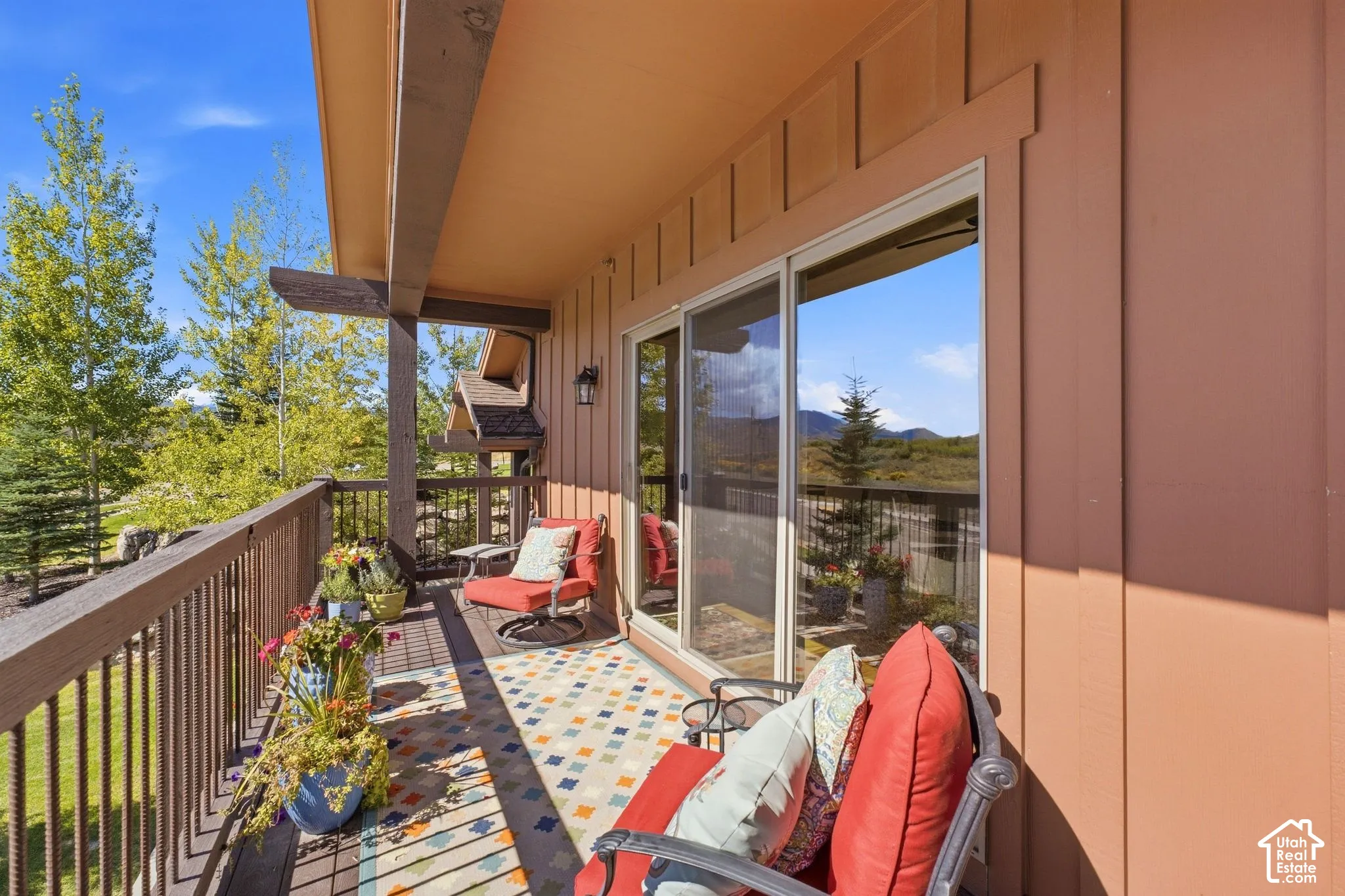 Covered balcony featuring vertical wood-style siding, structural support beams, metal railing, and sliding glass doors
