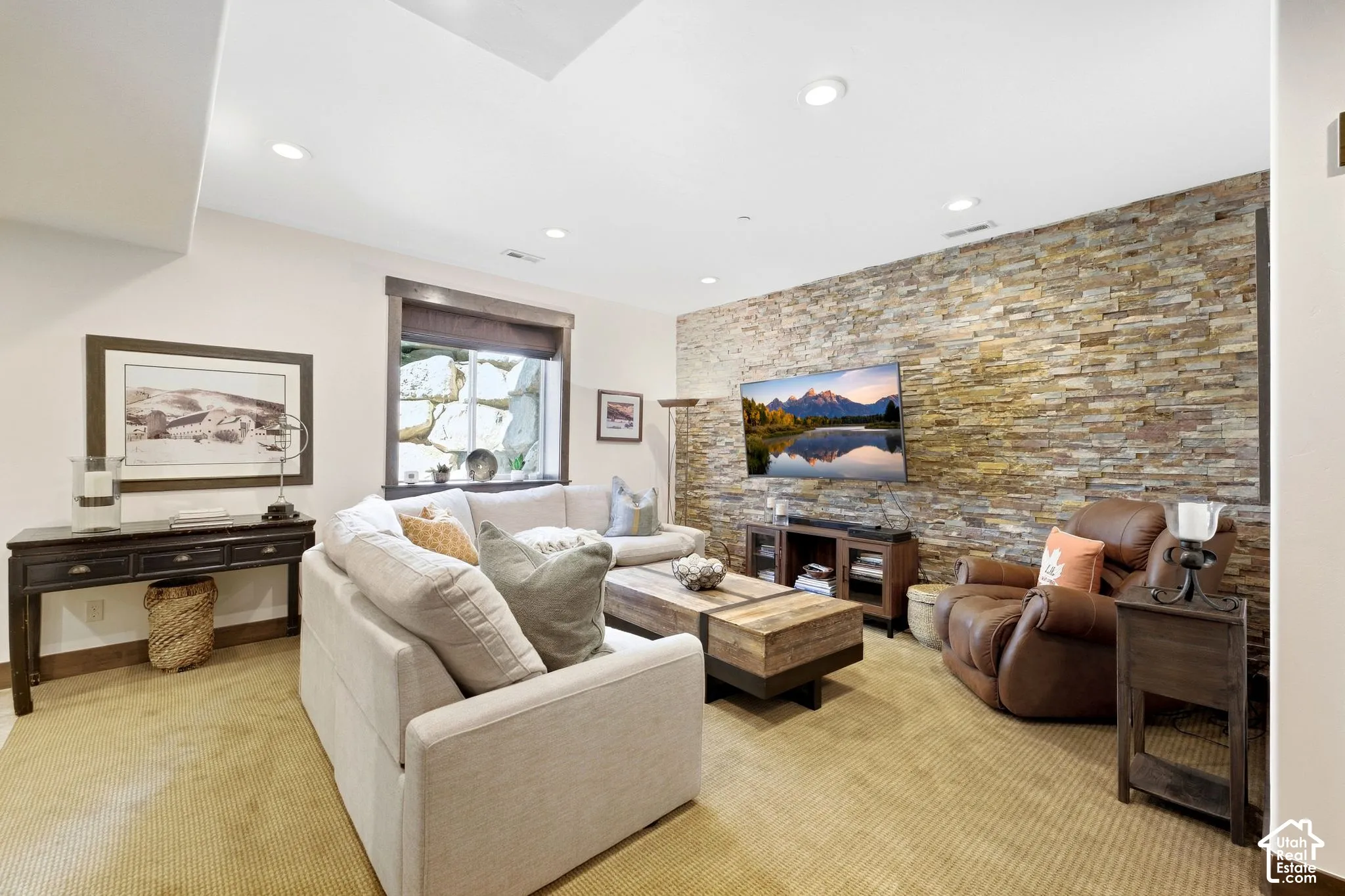Living space featuring a floor-to-ceiling natural stone accent wall and recessed lighting