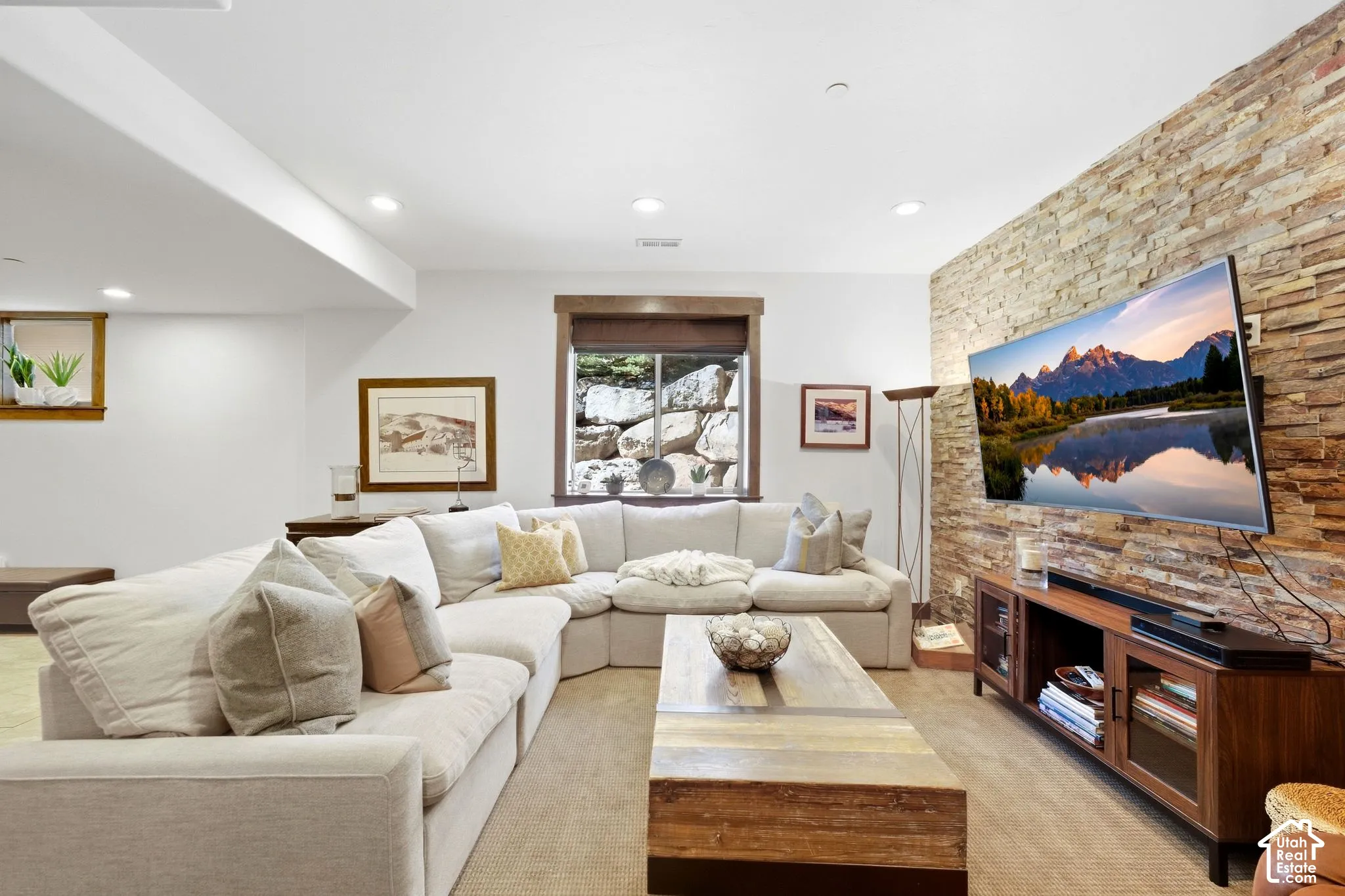 Stacked stone accent wall featuring natural textures, recessed lighting, and wooden window trim