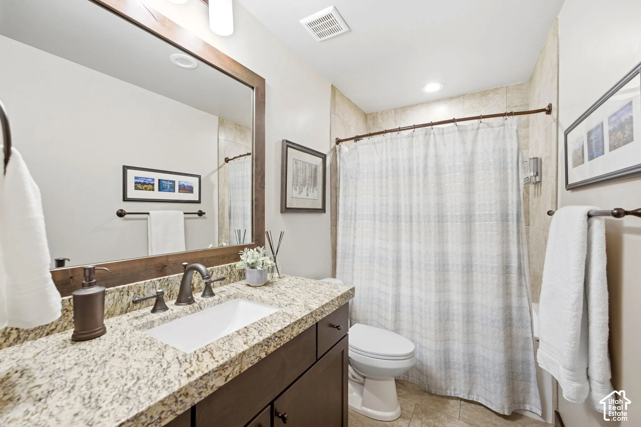 Dark-finish cabinetry paired with stone-surface countertops, integrated under-mount sink, dark-tone hardware, and full-wall mirror with wood-finish frame