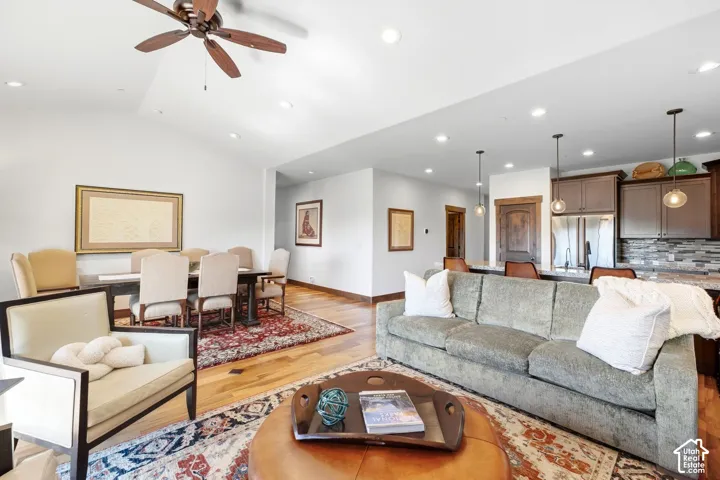 Vaulted ceilings, wood-finish flooring, recessed lighting, pendant kitchen island lighting, and ceiling fan