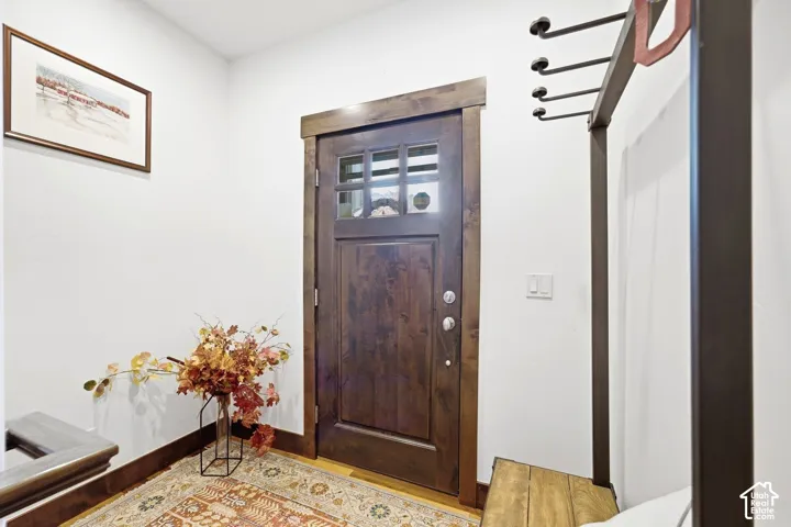 Solid wood door with a multi-pane glass insert and matching stained wood trim, accompanied by a built-in metal coat rack featuring integrated hooks and a wooden bench seat