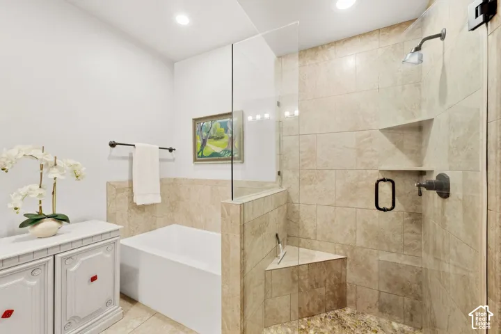 Bathroom featuring a deep soaking tub and a walk-in shower with stone-tile surround, integrated corner bench, frameless glass enclosure, and matte bronze hardware