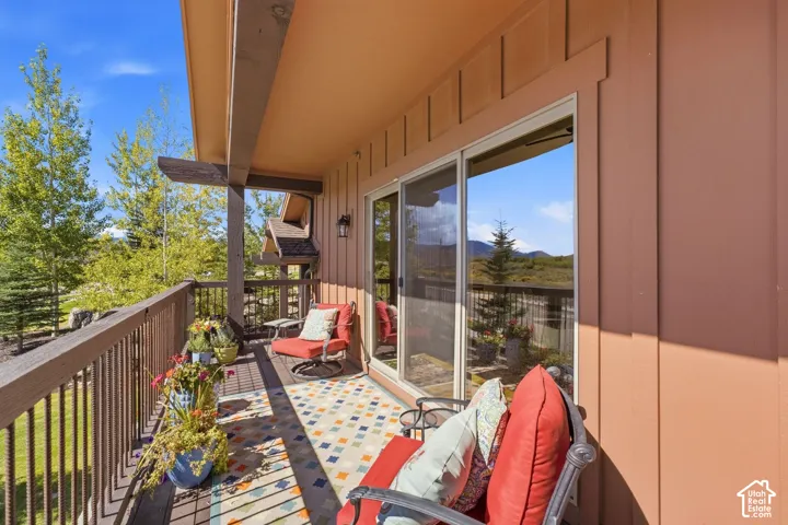 Covered balcony featuring vertical wood-style siding, structural support beams, metal railing, and sliding glass doors