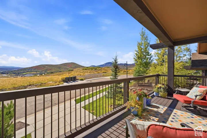 Covered balcony featuring dark-finished wood and metal railings and a mountain landscape backdrop