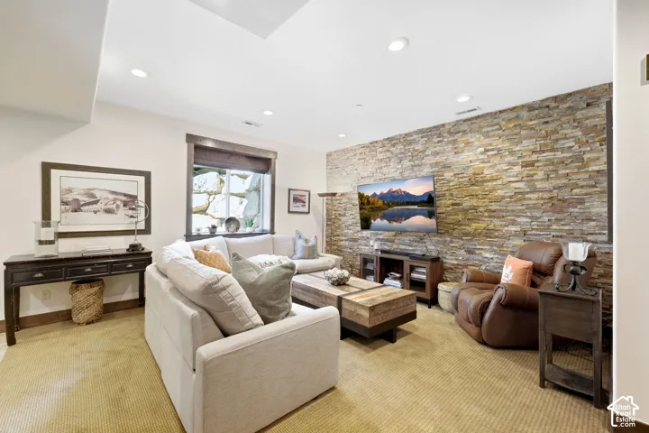 Living space featuring a floor-to-ceiling natural stone accent wall and recessed lighting