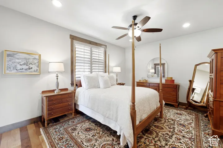 Wood-finish flooring, recessed lighting, ceiling fan with light fixture, and plantation shutters featuring stained wood trim