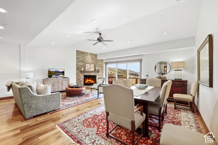 Open-concept area featuring vaulted ceilings, stone-surround corner fireplace with wood mantel, wood-finish flooring, and recessed lighting