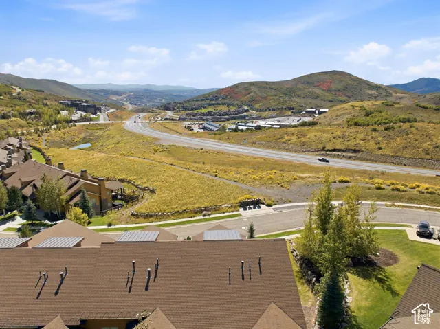 Aerial perspective featuring multi-level asphalt shingle roofing, integrated chimneys, and expansive surrounding mountain terrain