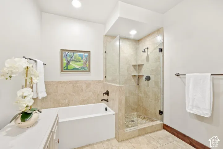 Bathroom featuring a deep soaking tub, separate glass-enclosed shower, stone-tile surround, and matt bronze hardware finishes