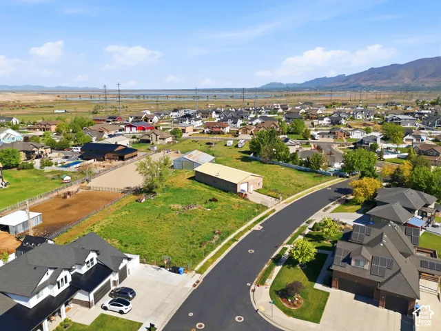 Expansive parcel featuring mature trees, fenced enclosure, and two detached outbuildings, set against a backdrop of mountain ranges