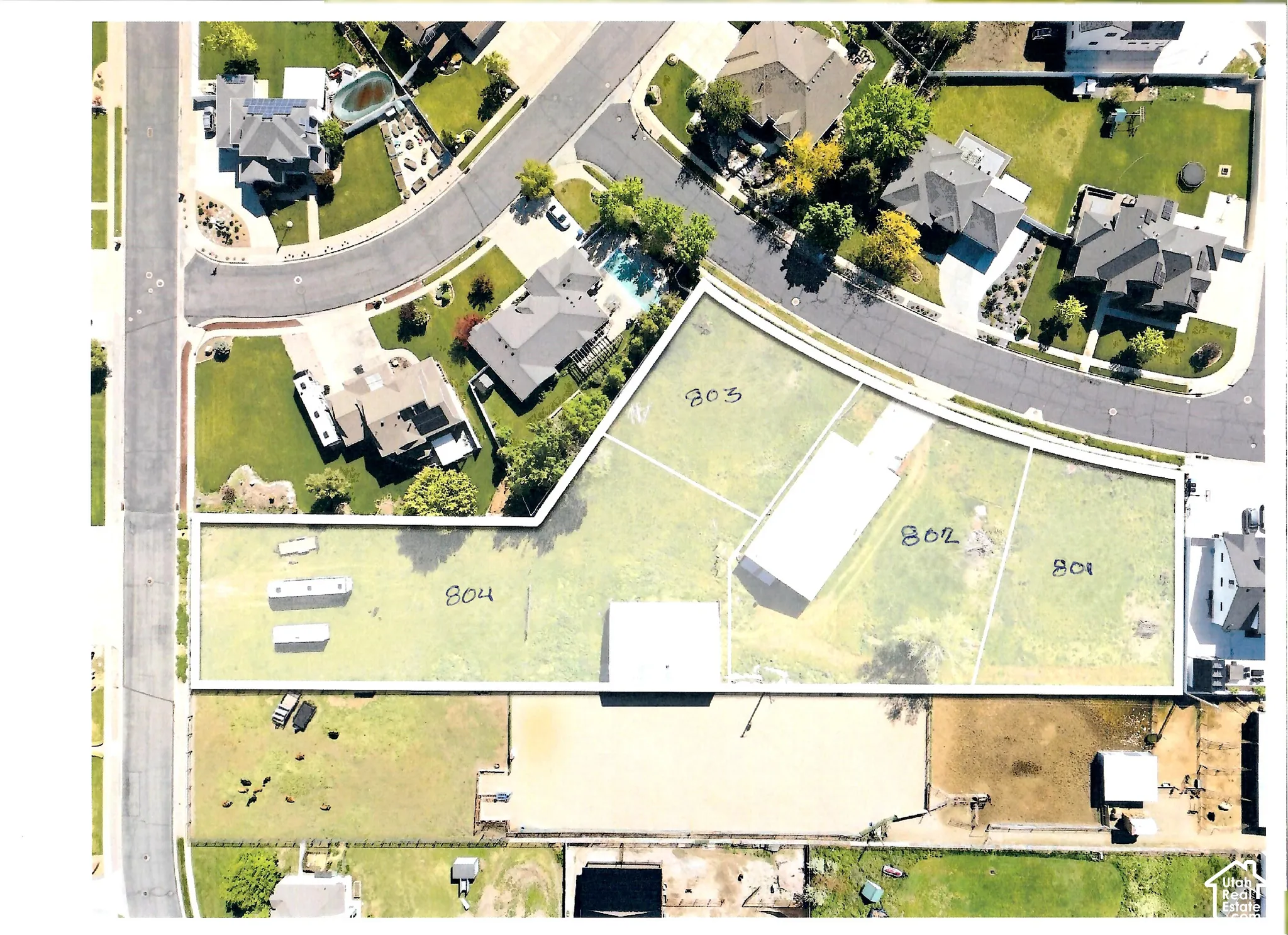 Aerial view of subdivided residential lots featuring expansive grass-covered terrain, clearly defined property boundaries, and direct street frontage