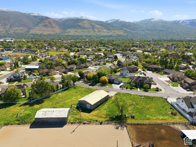 Expansive acreage featuring a metal-sided workshop, secondary storage structure, leveled arena, and a prominent mountain backdrop