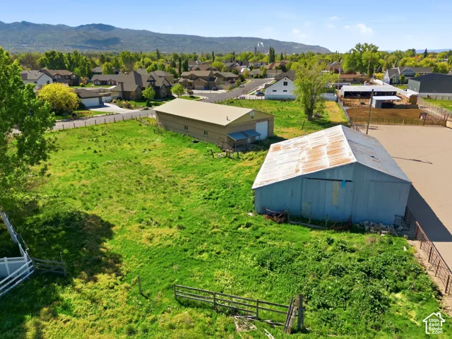 Expansive lot featuring two detached outbuildings, metal-sided structures, fencing, and a mountain backdrop