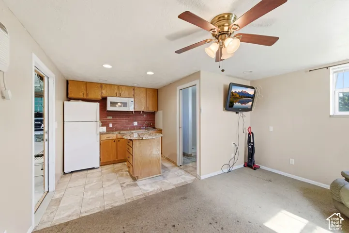 Kitchen featuring wood cabinetry, stone-finish countertops, a built-in microwave, and tile flooring, complemented by a ceiling fan with integrated lighting
