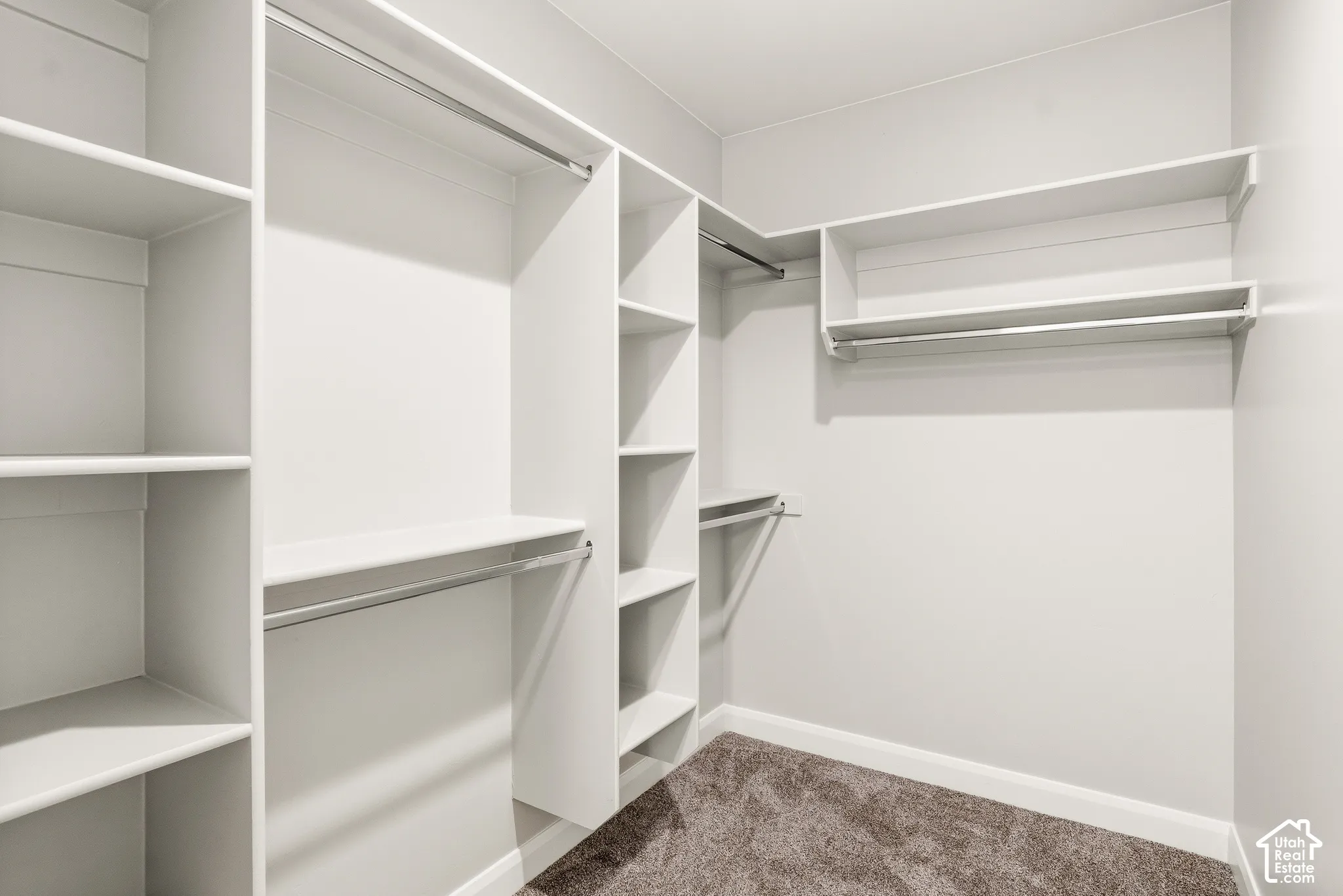 Walk-in closet featuring white built-in shelving, integrated storage cubbies, and dual-level metal hanging rods